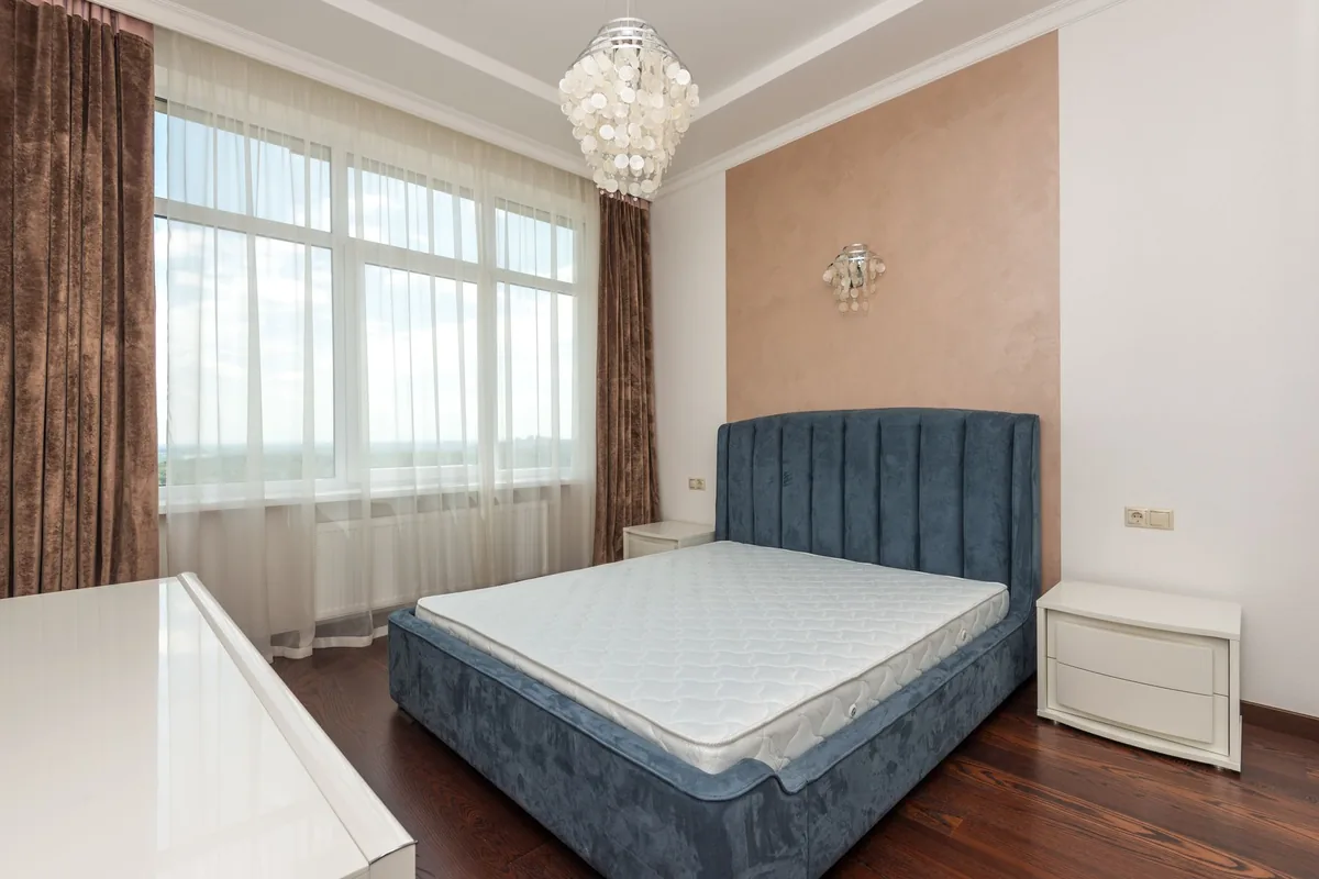 A bare mattress on an upholstered platform bed whose frame and headboard extend beyond the mattress on every side