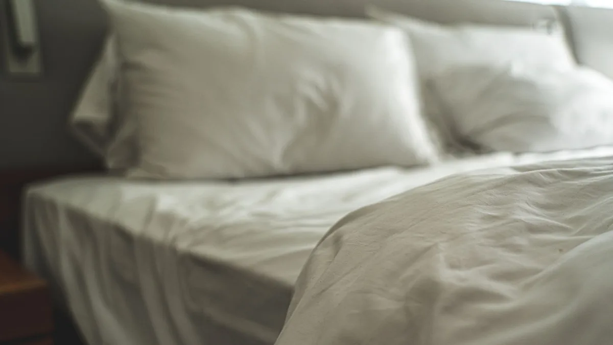 A bed made up with white sheets, white pillows and a white duvet