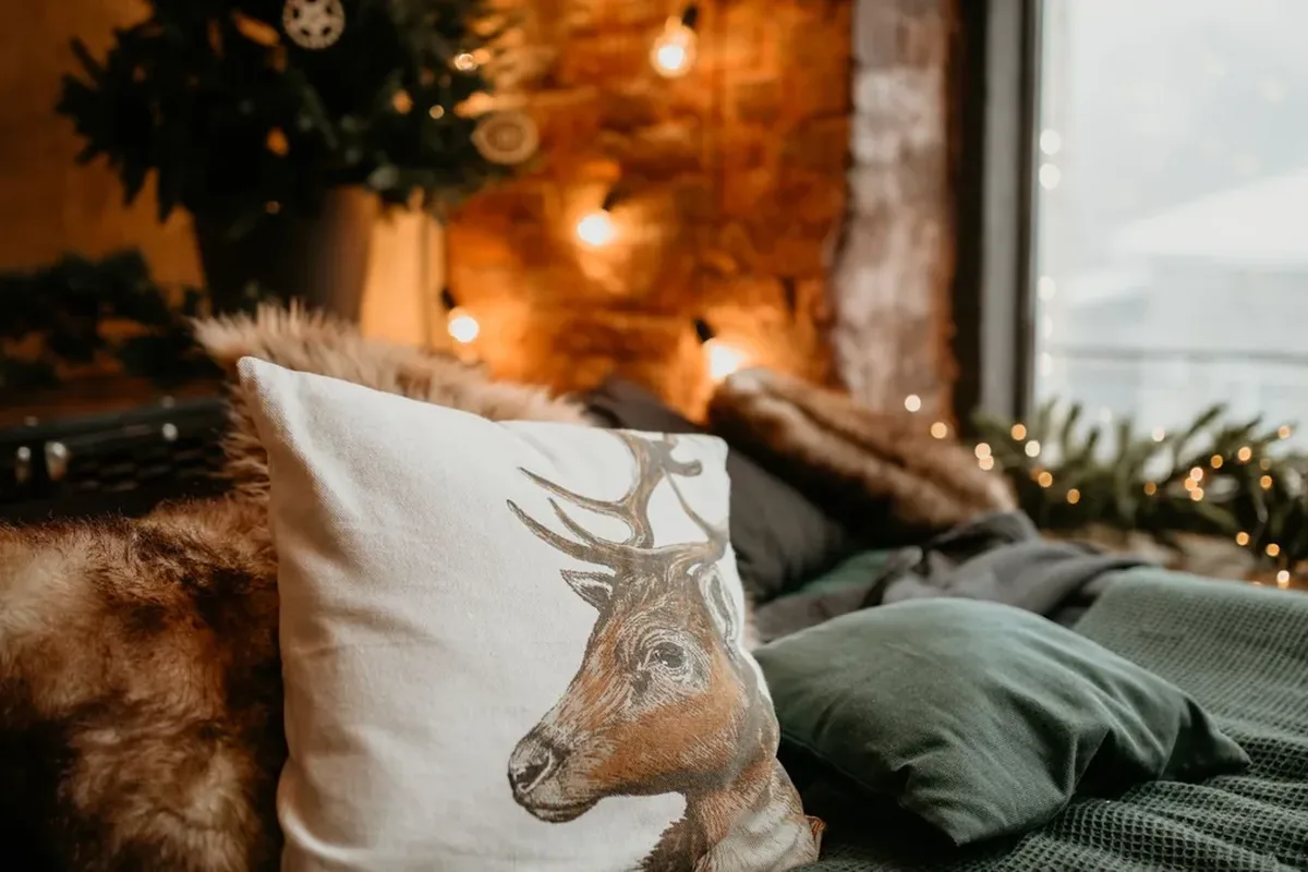 A bed with grey bedding and a decorative pillow in a warm bedroom