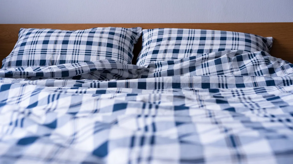 A bed made up with blue plaid bedding in a modern bedroom