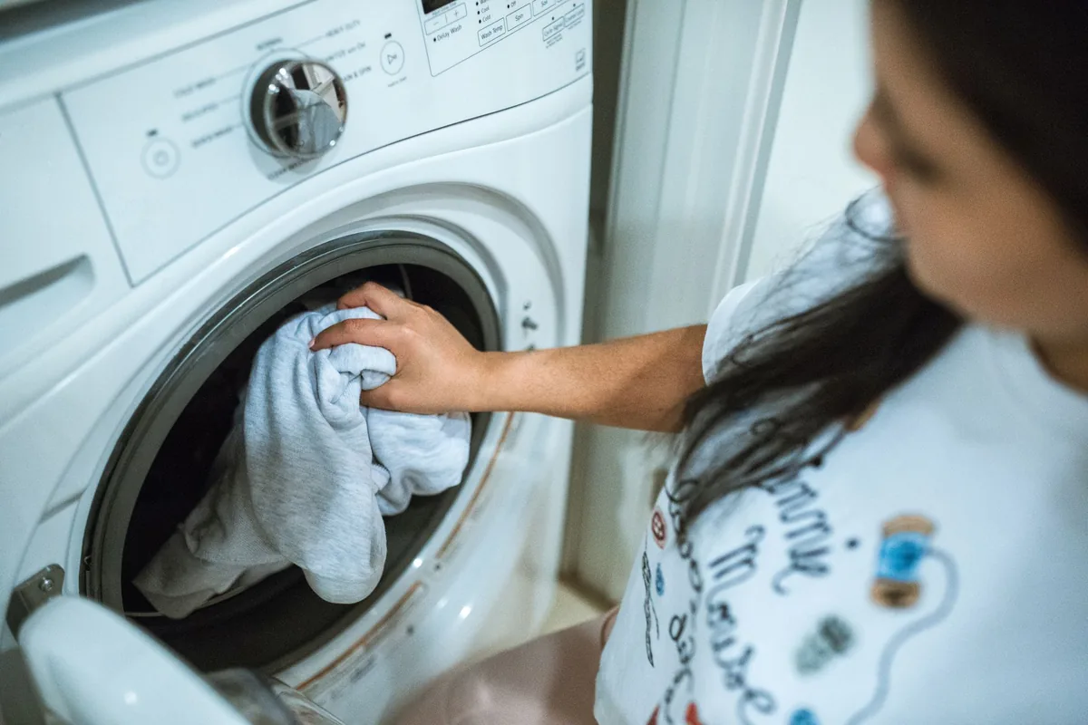 A woman loading laundry into a front-loading washing machine