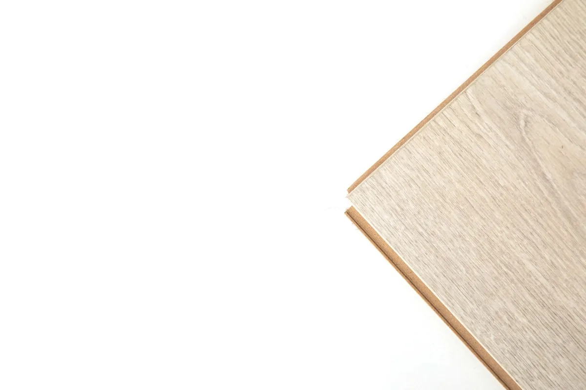 The edge profile of a light wood-look plank lying against a white background