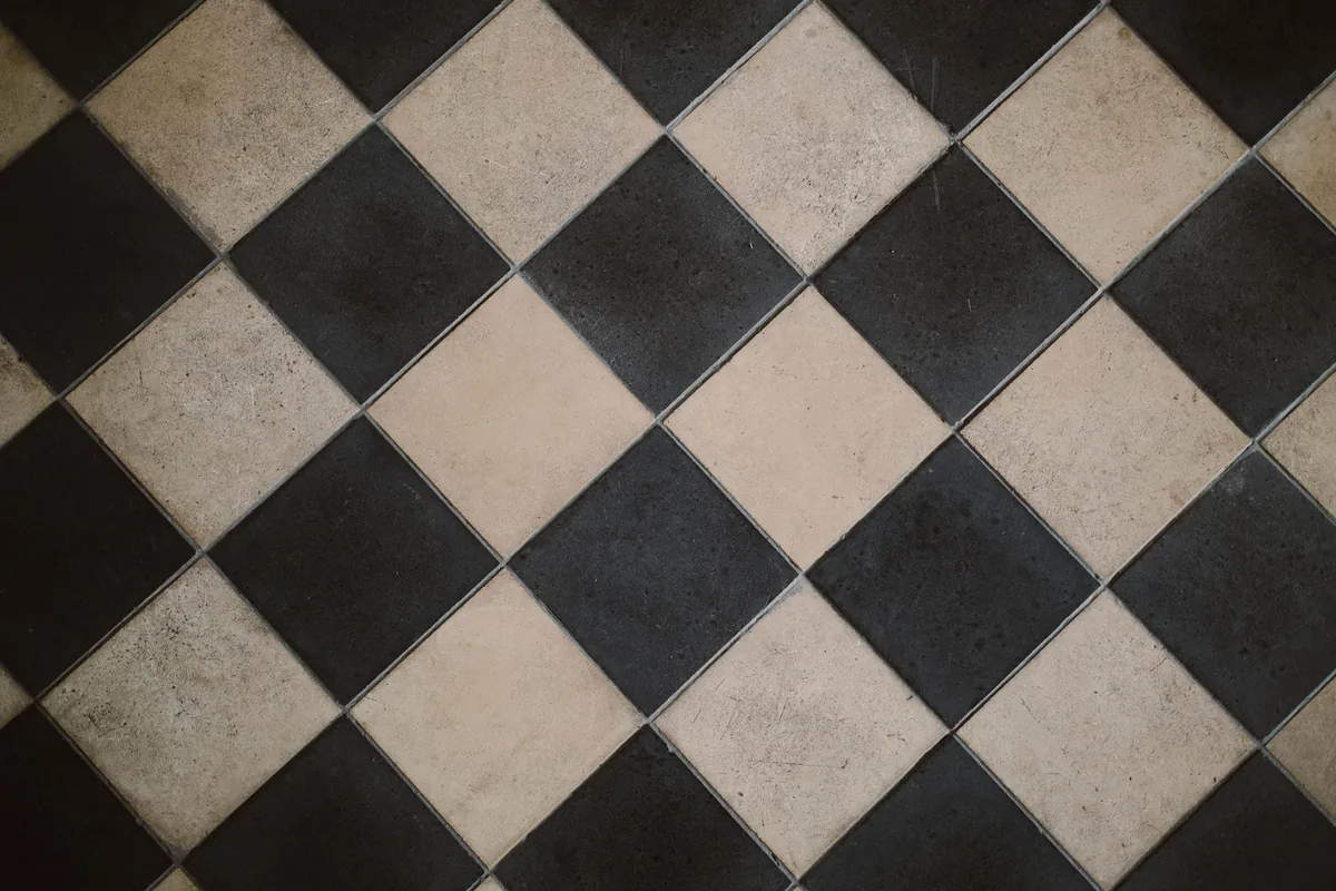 Black and cream square floor tiles laid on the diagonal with thin gray grout joints