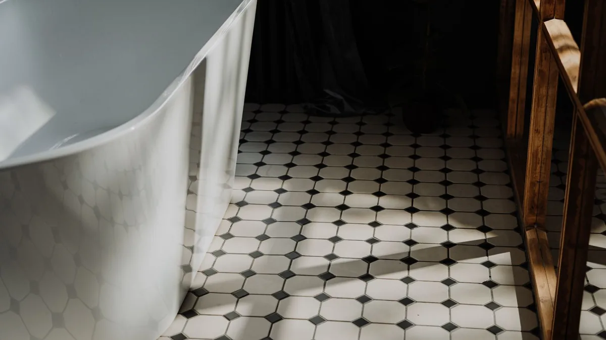 White octagon floor tiles with small black square inserts beside a freestanding white bathtub