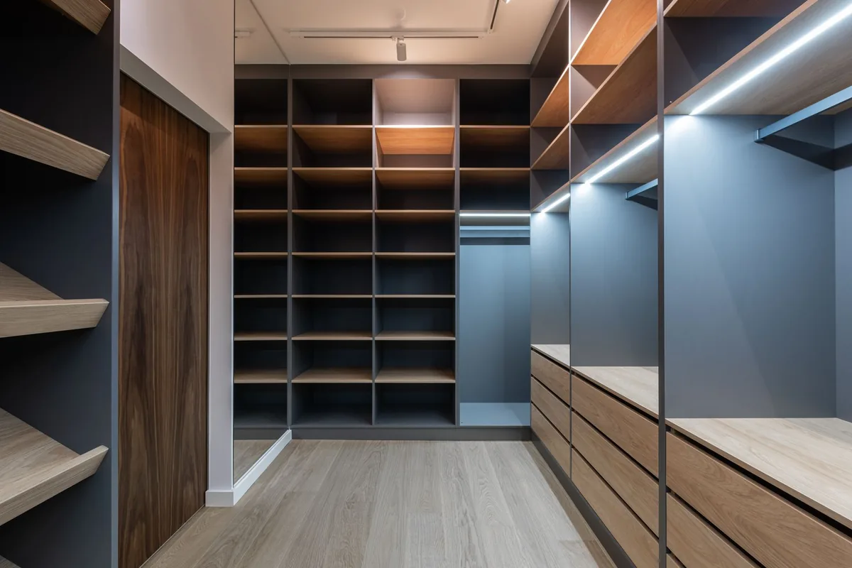 A walk-in closet with angled shoe shelves on the left, open cubbies at the back and drawers on the right