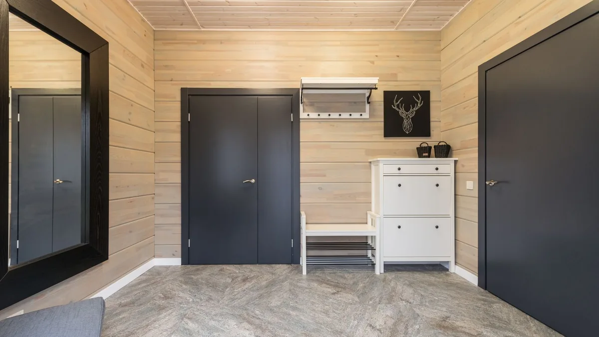 A hallway with a white bench over a two-tier shoe rack next to a white shoe cabinet with flip-down doors
